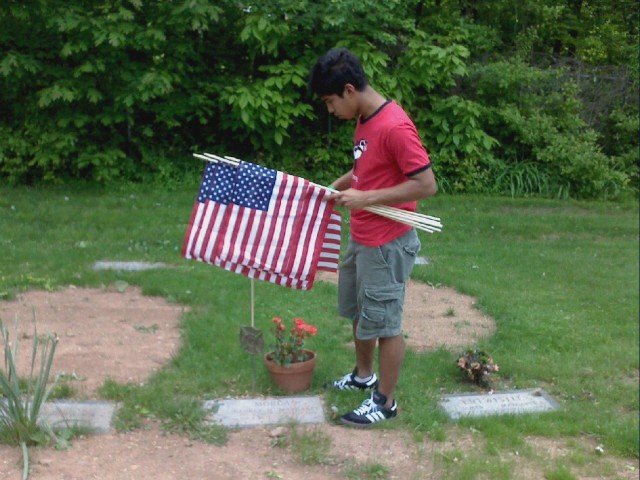 Shudipto Rahman places a flag at the gravesite of a deceased firefighter.  5/24/08